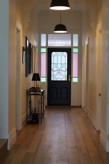 Restored villa hallway with wide timber floors and a leadlight front door