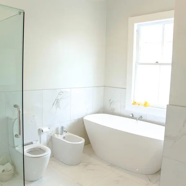 After: Remuera bathroom renovation with freestanding bath beneath a sash window